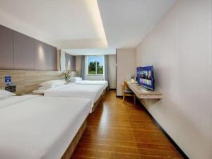 a hotel room with four beds and a television at Wenxing Hotel Guangzhou Huajing Xincheng Branch in Guangzhou