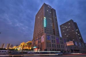 un palazzo alto con un cartello verde di City Comfort Inn Wuhan Hankou Bei Light Rail Station a Wuhan
