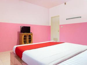 ein rosa-weißes Schlafzimmer mit einem Bett und einem Fernseher in der Unterkunft OYO 627 Sai Thai Garden Home Travel in Ban Klang