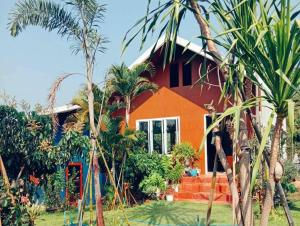 a red house with palm trees in front of it at Mon Chang Home in Mae Rim
