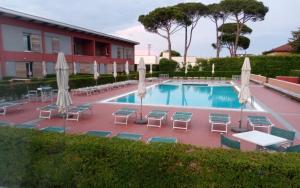a swimming pool with chairs and umbrellas at Residence Ca Tron Mare in Jesolo