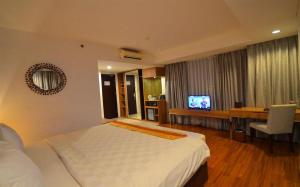 a bedroom with a bed and a desk and a television at Arch Hotel Bogor in Bogor