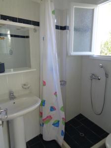 łazienka z zasłoną prysznicową i umywalką w obiekcie Green View Apartments w mieście Agios Nikitas