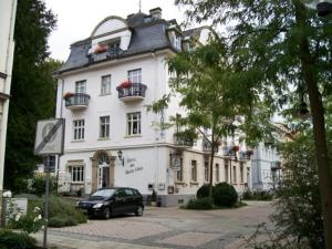 een zwarte auto geparkeerd voor een wit gebouw bij Hotel Weisses Haus in Bad Kissingen