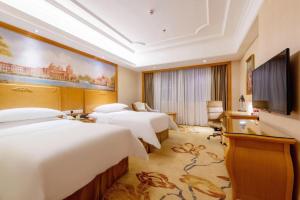 深圳Vienna International Hotel Shenzhen North Station Branch的酒店客房设有四张床和平面电视。
