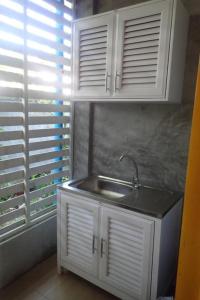 une cuisine avec des armoires blanches, un évier et une fenêtre dans l'établissement Rommai Rimnaam Resort, à Ban Bang Rin (1)