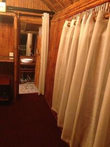 a bathroom with white shower curtains and a sink at Baansuanpai Noppakao in Pong Talong +16 photos