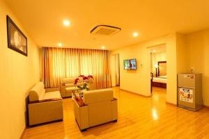 a living room with a couch and chairs and a room with a bed at New Palace Bac Lieu Hotel in Bạc Liêu