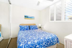 Un dormitorio con una cama azul y una ventana. en The Headlands Apartment 16, en Alexandra Headland