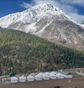 a snow covered mountain with a bunch of white tents at Olgo camps and cafe Chhitkul in Chitkul