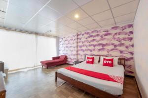a bedroom with a large bed and a red chair at OYO 1152 Hongpak Mint in Ban Bang Saen (1)