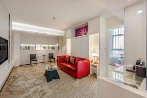 a living room with a red couch and a table at Holiday Villa Hotel & Residence Shanghai Jiading in Xuhang