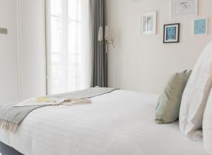 a white bed in a room with a window at 1er Etage Opéra in Paris +40 photos