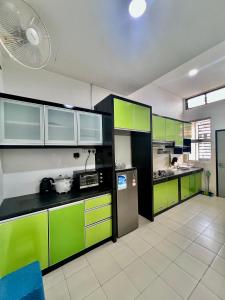 a large kitchen with green cabinets and a fan at Casa Damai Kuantan - near Taman Tas, SEMSAS, UMP,Airport, Uia, Matrik Gambang, Menara 188, 4bilik-3AC 1kipas, Ruang Tamu kipas in Kuantan