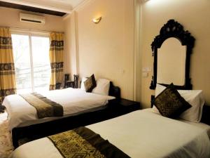 Un dormitorio con dos camas y un espejo y una ventana. en Kangaroo Hostel, en Hanói