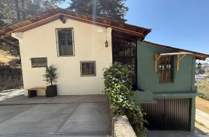 a small white and green building with a porch at Finca Rolando in Tlalpujahua de Rayón