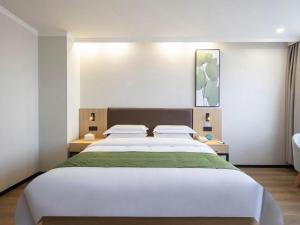 une chambre avec un grand lit blanc avec deux tables de nuit dans l'établissement GreenTree Inn Hefei Feidong Guiwang Road Luzhou Medical School Business Hotel, à Feidong 158 autres photos