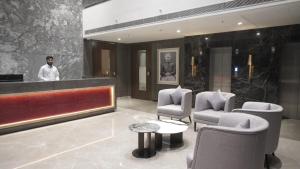 a man standing in a lobby with chairs and a counter at The LEGACY HOTEL JAMSHEDPUR in Jamshedpur