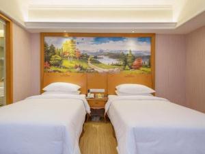two beds in a room with a painting on the wall at Vienna International Hotel Shanghai Dishui Lake Lingang Wanda in Shanghai +225 photos
