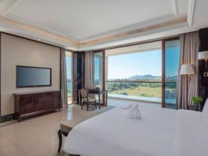 a bedroom with a large bed and a large window at Jinsha Seaview Hotel Sanya in Sanya