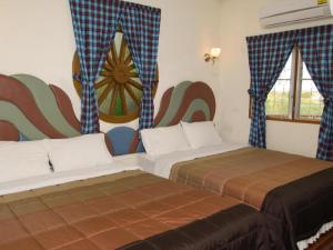two beds in a room with a mural on the wall at Phucome Resort in Campson