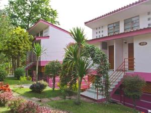 a pink and white house with palm trees in front at Phucome Resort in Campson