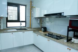 a white kitchen with a sink and a stove at Ivy Residence in Jiaozhou +6 photos