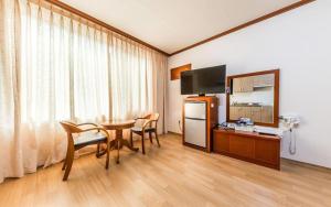 Zimmer mit einem Tisch und einem Kühlschrank sowie einem Tisch und Stühlen in der Unterkunft Gangneung Gyeongpodae Gangneung Motel in Kangmun