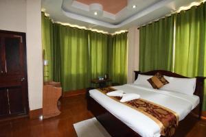 a bedroom with a large bed with green curtains at PXT Hotel in Ban Sivilai +21 photos