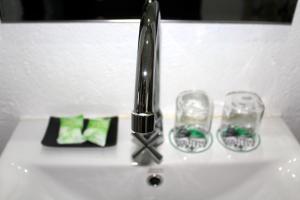 a sink with a faucet and two glasses on it at EcoTravel Cottages Bukit Lawang in Bukit Lawang
