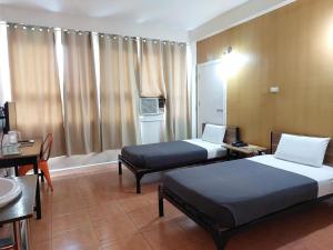 a hotel room with two beds and a table and a desk at My Hotel Davao in Davao City +176 photos