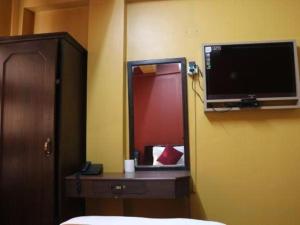 a bedroom with a television and a desk with a bed at OYO 381 Hotel Pashupati Plaza in Kathmandu