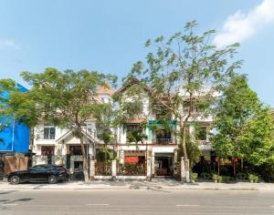 a large white building with trees in front of it at Kim's Villa Hoi An in Hoi An