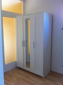 Zimmer mit einem weißen Schrank und einem Spiegel in der Unterkunft Ferienwohnung J.Weber in Hornbach