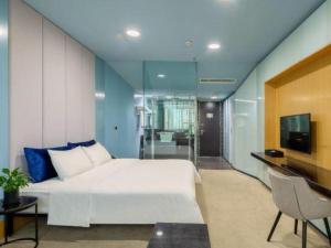 a bedroom with a white bed and a television at Dongying Blue Horizon Xinyue Hotel in Dongying