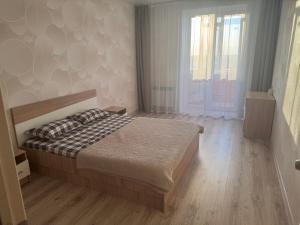 a bedroom with a bed and a large window at 2-х комнатная квартира в районе Костанай плаза in Kostanay