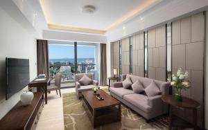 a living room with a couch and a large window at Sanya Shuangda Adelaide In Resort Hotel in Sanya