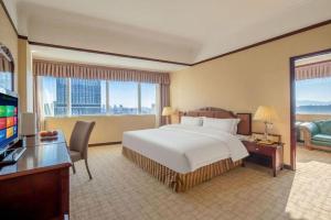 a hotel room with a bed and a desk and a television at Telecom International Hotel in Kunming