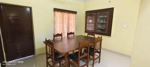 a dining room with a wooden table and chairs at Sukumar Villas in Nellore