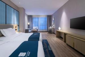 a hotel room with a large bed and a flat screen tv at Echarm Hotel Danzhou Xiari Plaza in Danzhou +257 photos