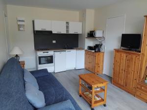 a living room with a blue couch and a kitchen at Appartement refait à neuf en 2025 in Cabourg