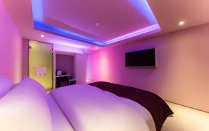 ソウルにあるBobo Hotel Hongdaeの壁に紫色のライトがありベッドがある寝室