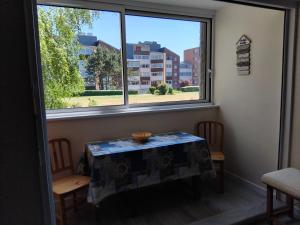 a table and chairs in a room with a window at Appartement refait à neuf en 2025 in Cabourg