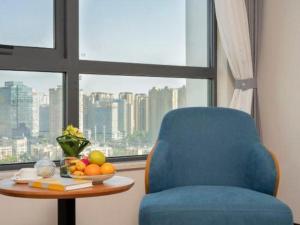 a room with a blue chair and a table and a window at Kunming Guihua Hotel in Kunming