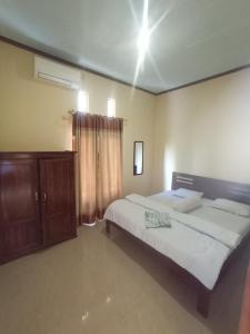 a bedroom with two beds and a wooden cabinet at PENDIK Home Stay in Labuan Bajo