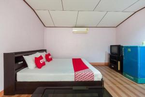 une chambre avec un lit avec des oreillers rouges et une télévision dans l'établissement OYO 1143 Phet Luran Thai Resort Kohchang, à Ko Chang