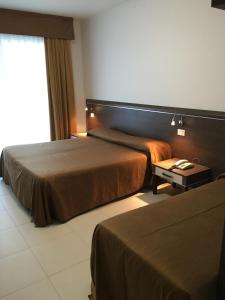 una camera d'albergo con due letti e un tavolo di Hotel Bellevue a Lignano Sabbiadoro
