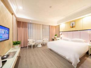 una camera d'albergo con un grande letto e una TV di mingjia hotel a Yiwu