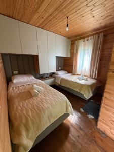 a bedroom with two beds and a wooden ceiling at Bujtina ZEMRA TRADITES in Theth +20 photos