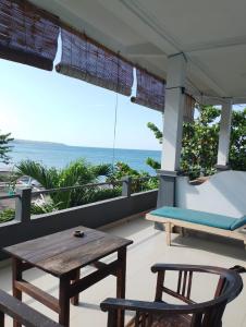 a porch with a table and chairs and the ocean at Kadek Homestay in Amed